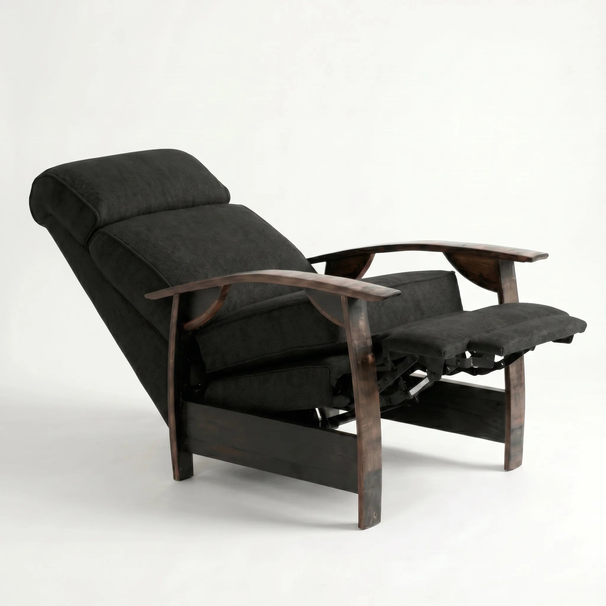 Black plush fabric whiskey barrel recliner reclined with footrest extended and oak whiskey-barrel stave armrests, on a white background