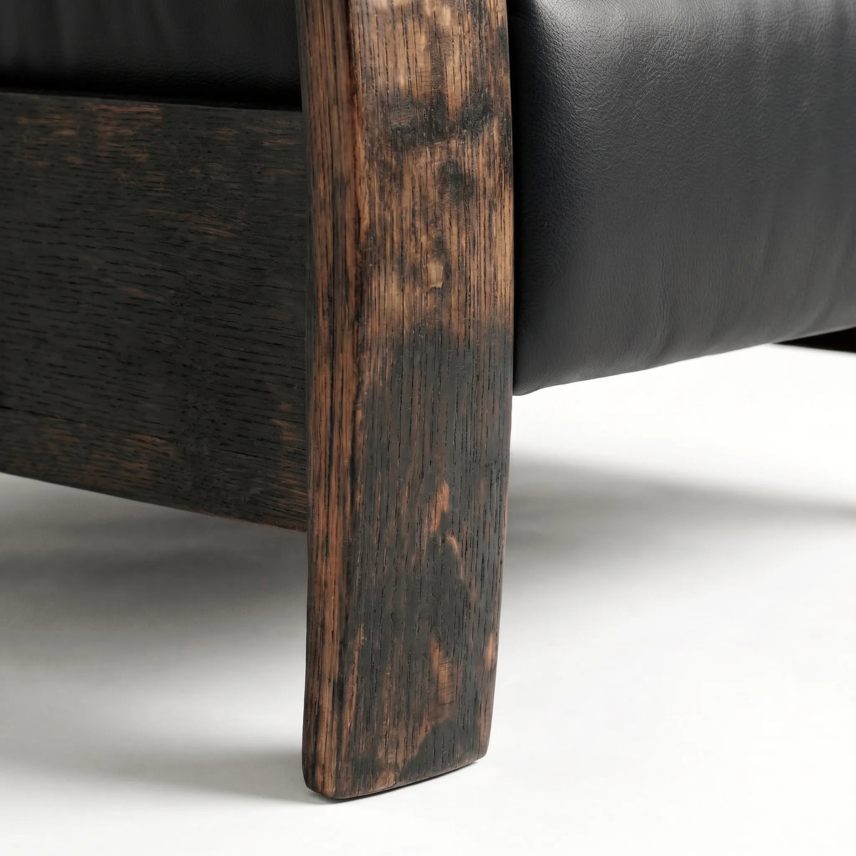 Close-up of the Big & Tall whiskey barrel recliner's oak whiskey-barrel stave leg in black leather, on a white background