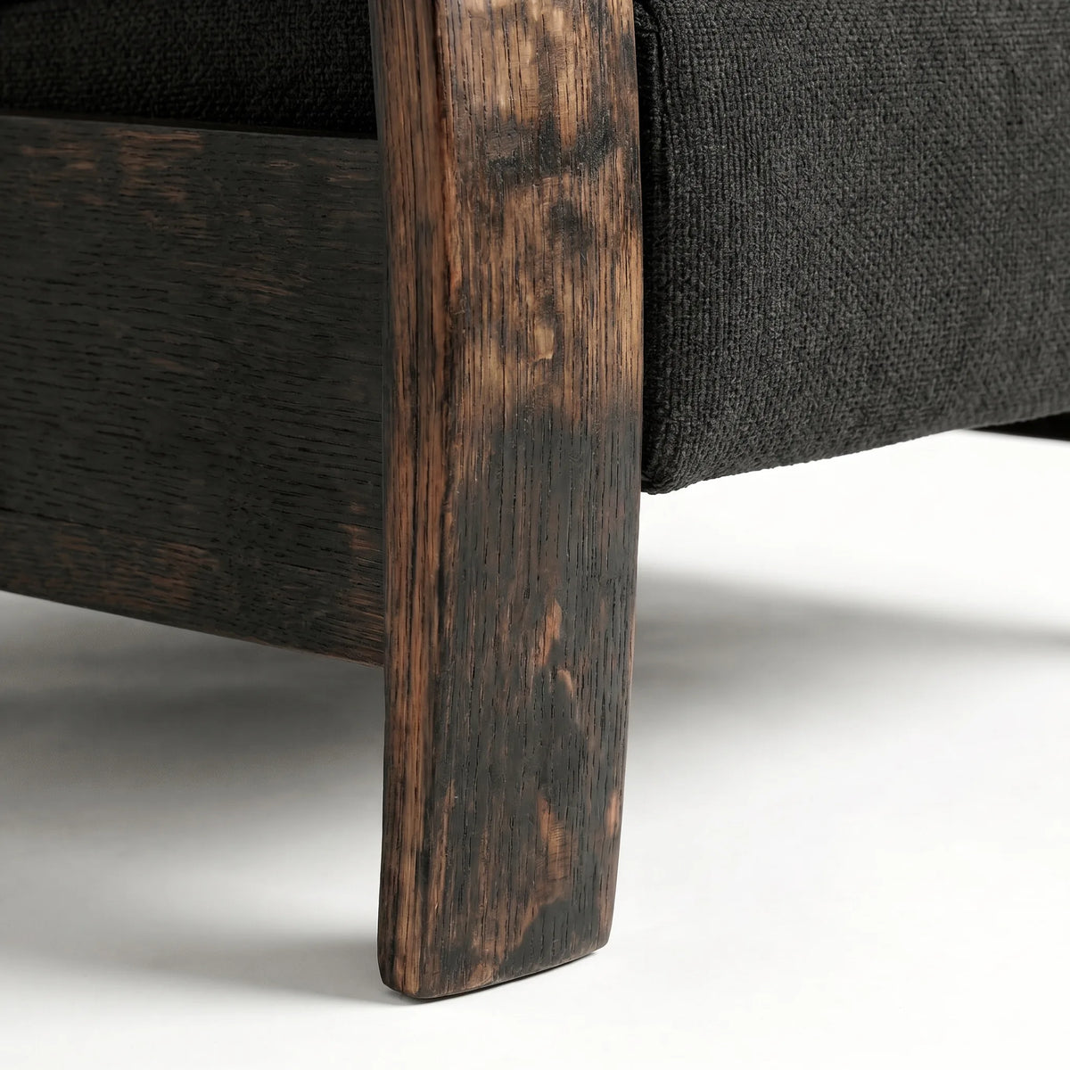Close-up of the whiskey barrel recliner's oak whiskey-barrel stave leg in black plush fabric, on a white background