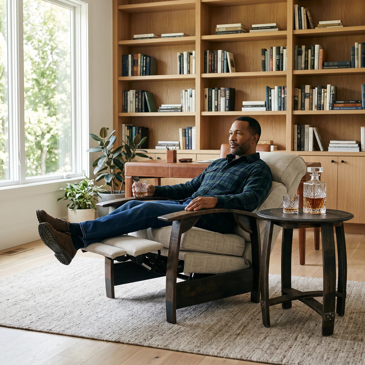 Man relaxing in an oatmeal gray plush fabric whiskey barrel recliner in a sunlit home study