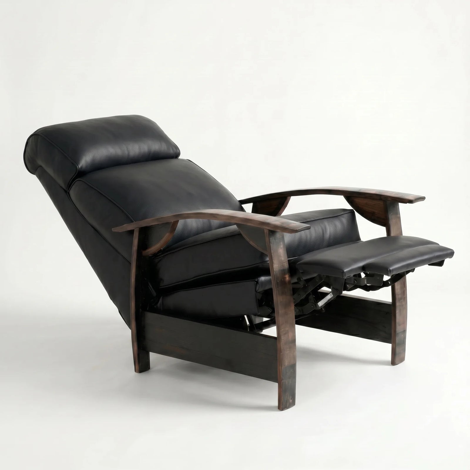 Black leather whiskey barrel recliner reclined with footrest extended and oak whiskey-barrel stave armrests, on a white background