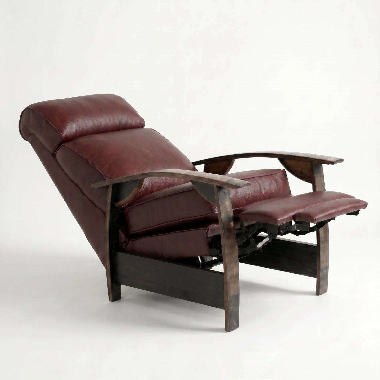 Oxblood leather whiskey barrel recliner reclined with footrest extended and oak whiskey-barrel stave armrests, on a white background