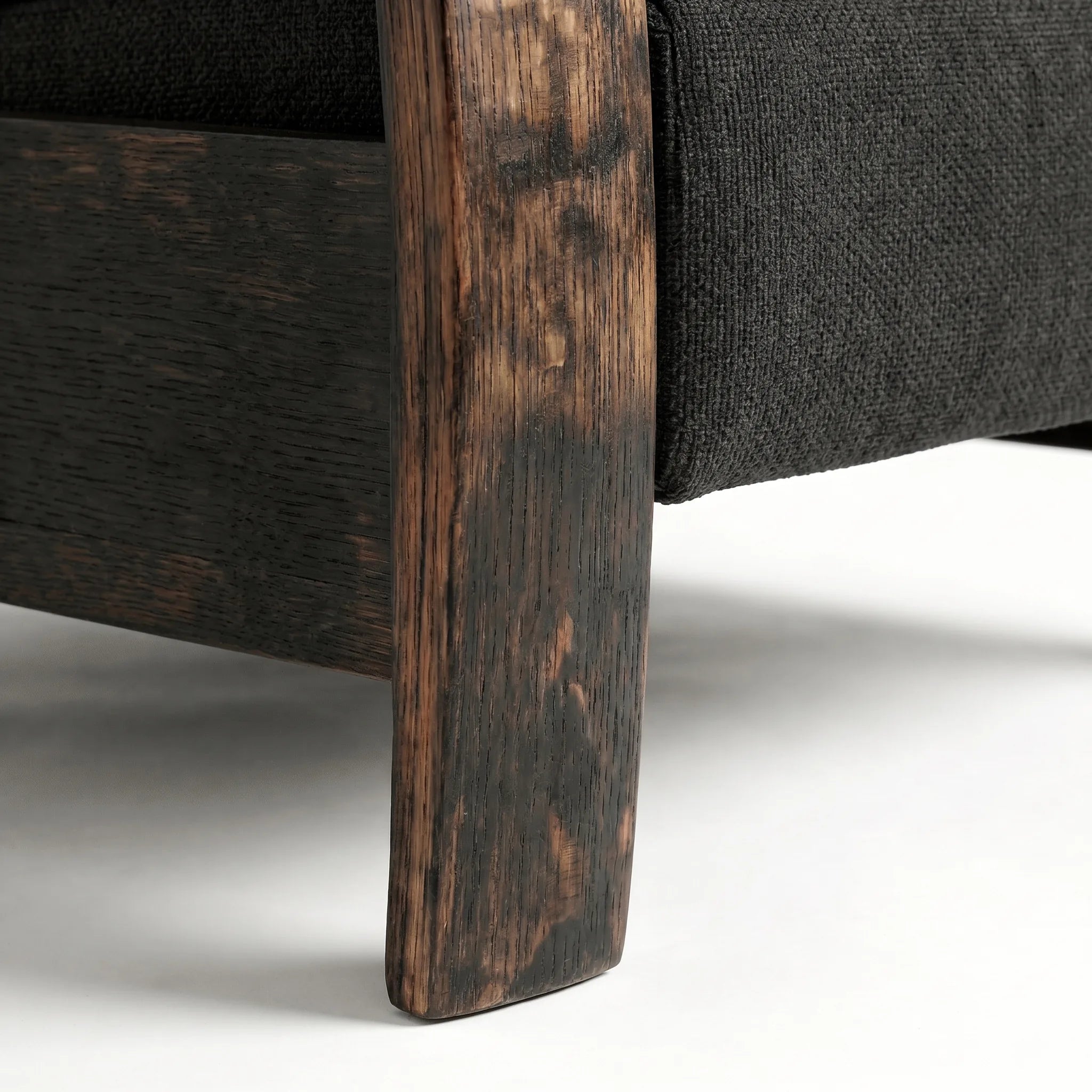 Close-up of the Big & Tall whiskey barrel recliner's oak whiskey-barrel stave leg in black plush fabric, on a white background