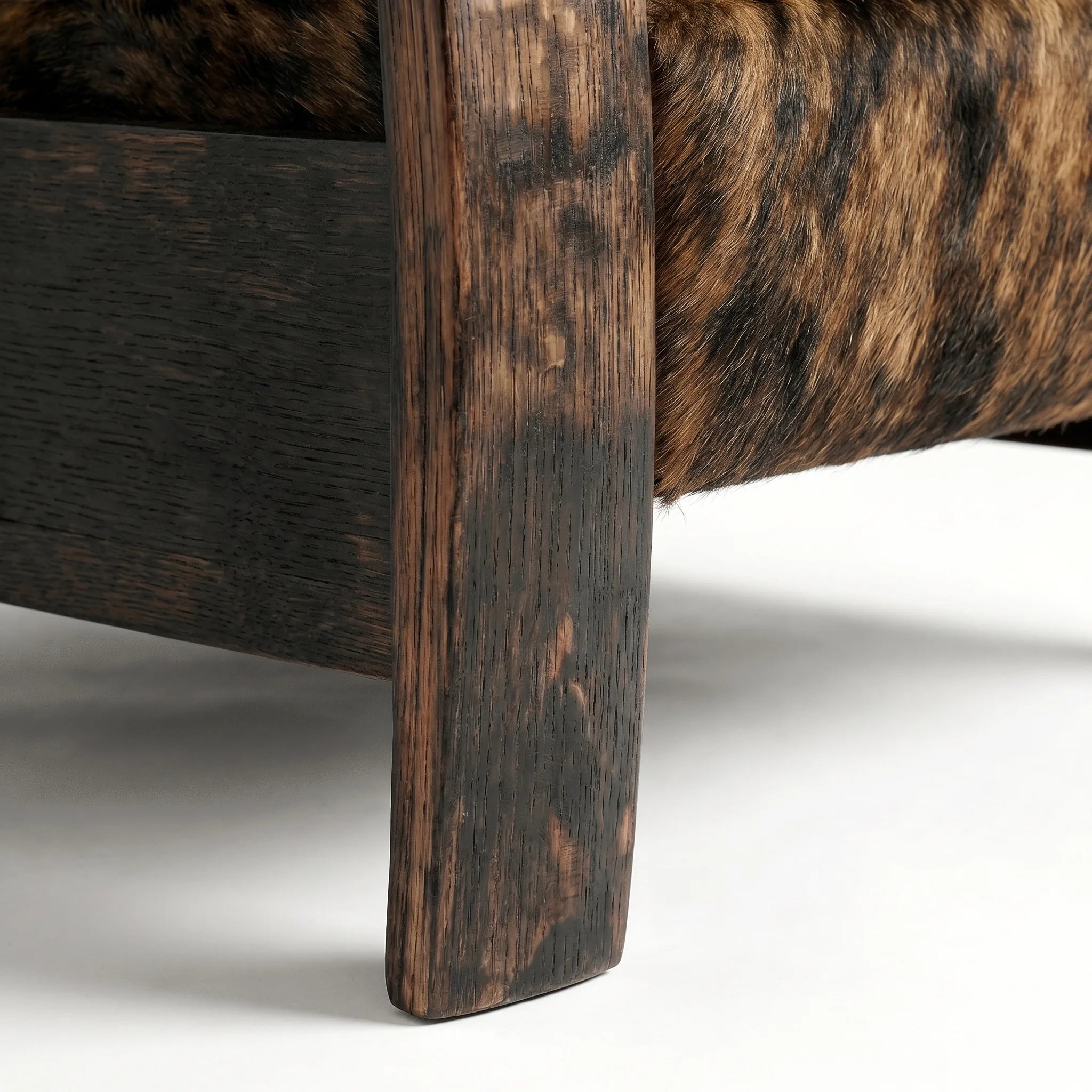 Close-up of the Big & Tall whiskey barrel recliner's oak whiskey-barrel stave leg in brindle cowhide, on a white background