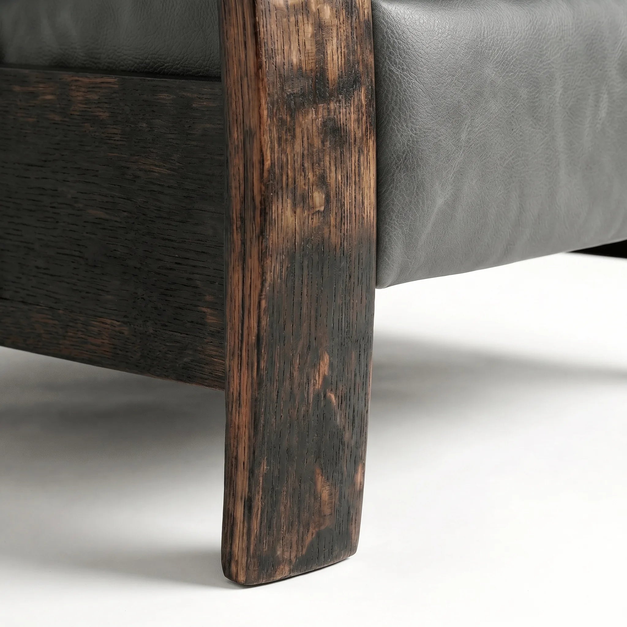 Close-up of the Big & Tall whiskey barrel recliner's oak whiskey-barrel stave leg in slate gray leather, on a white background