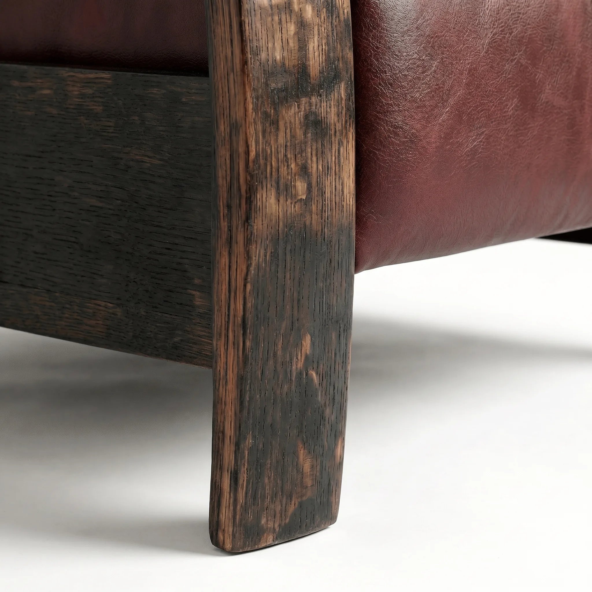 Close-up of the Big & Tall whiskey barrel recliner's oak whiskey-barrel stave leg in oxblood leather, on a white background
