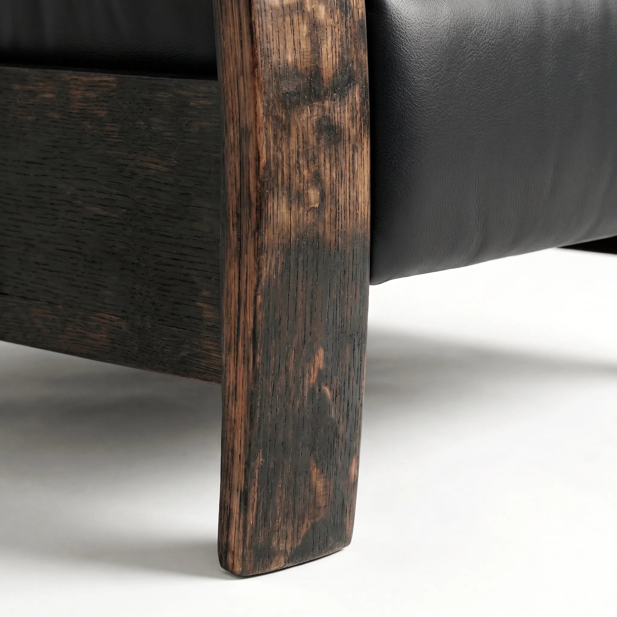 Close-up of the Big & Tall whiskey barrel recliner's oak whiskey-barrel stave leg in black leather, on a white background