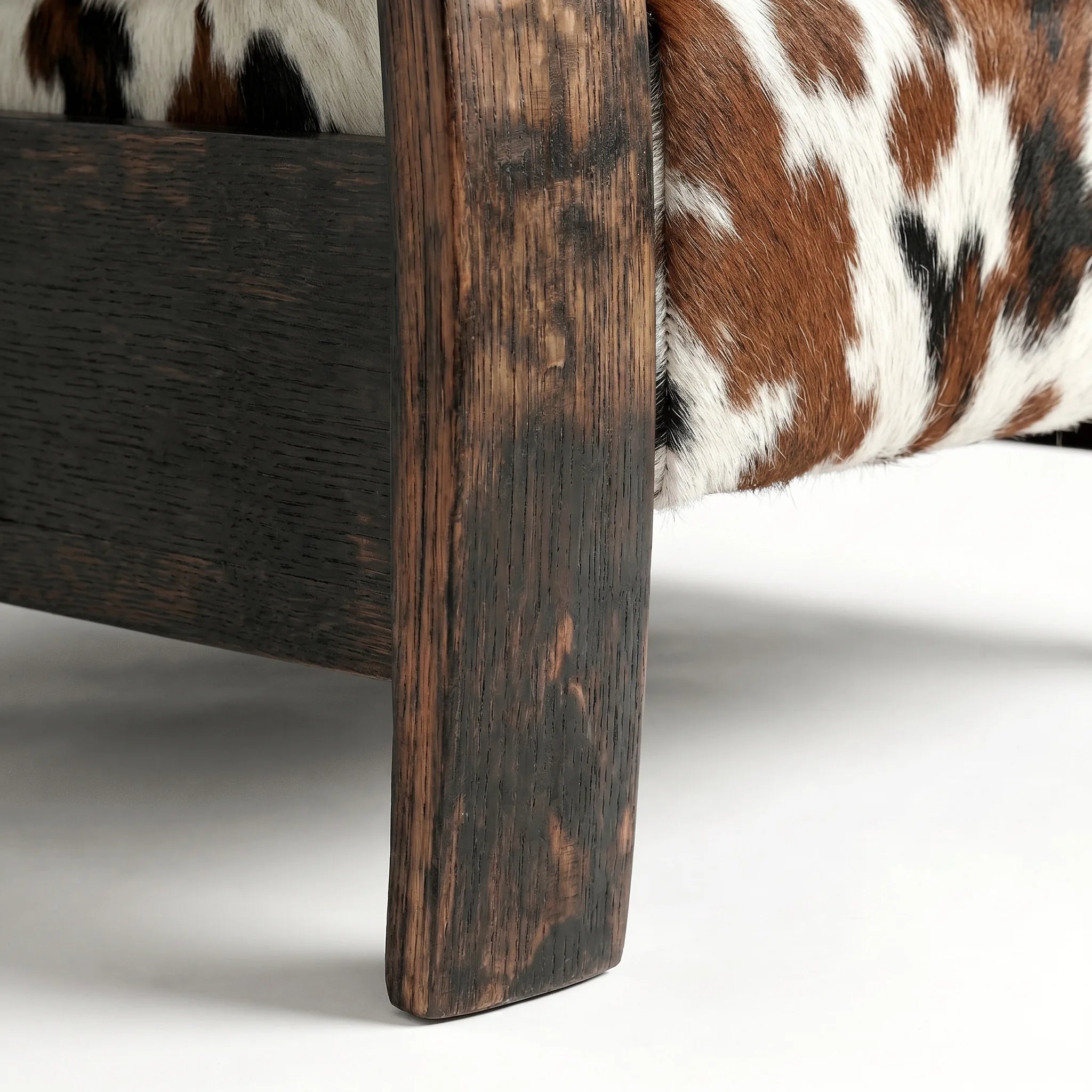 Close-up of the Big & Tall whiskey barrel recliner's oak whiskey-barrel stave leg in tri-color cowhide, on a white background