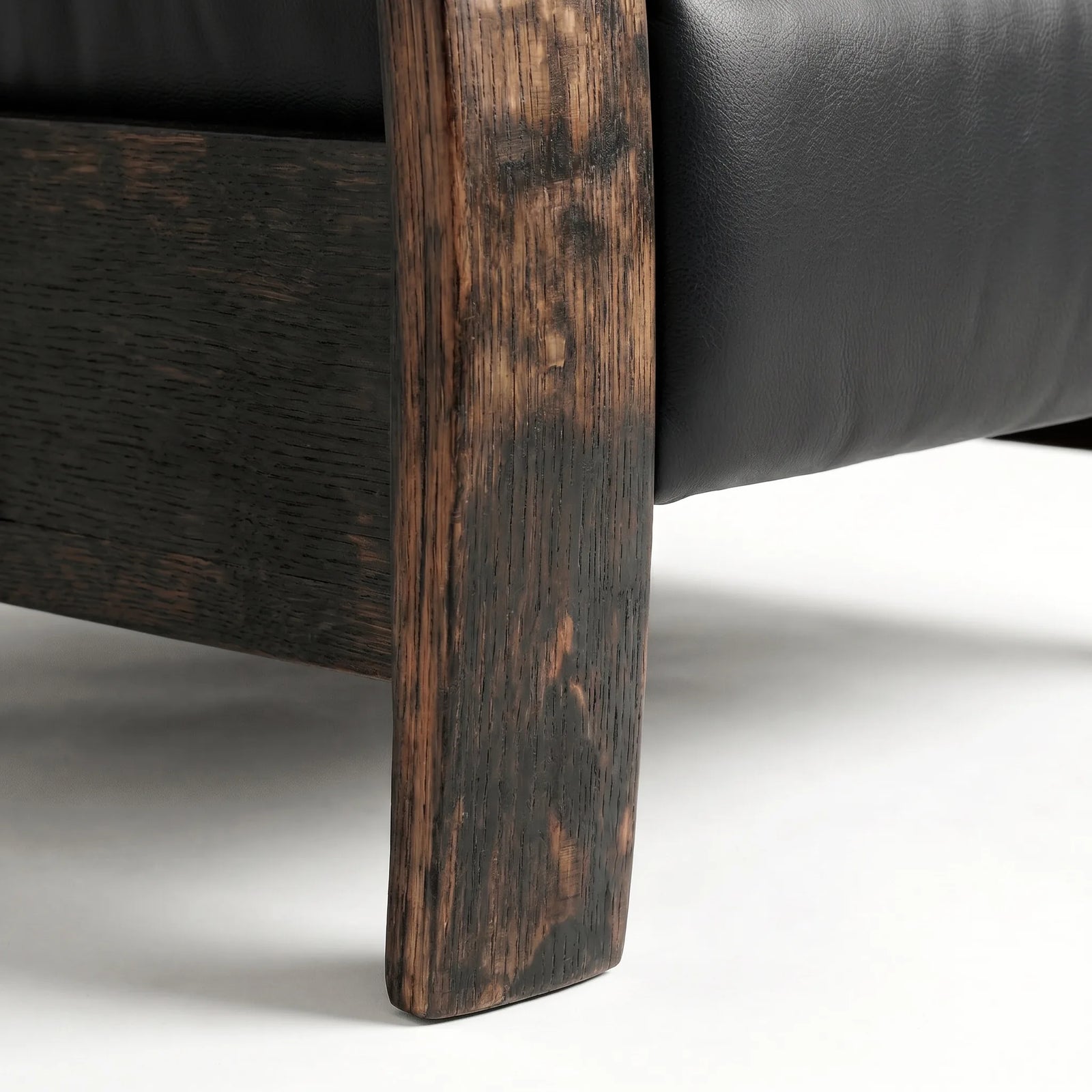 Close-up of the whiskey barrel recliner's oak whiskey-barrel stave leg in black leather, on a white background